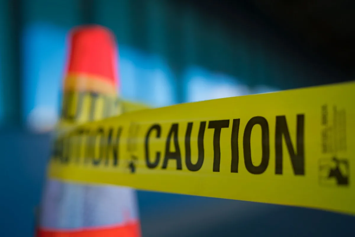 Yellow caution tape strung across a hazard cone on a wet floor.
